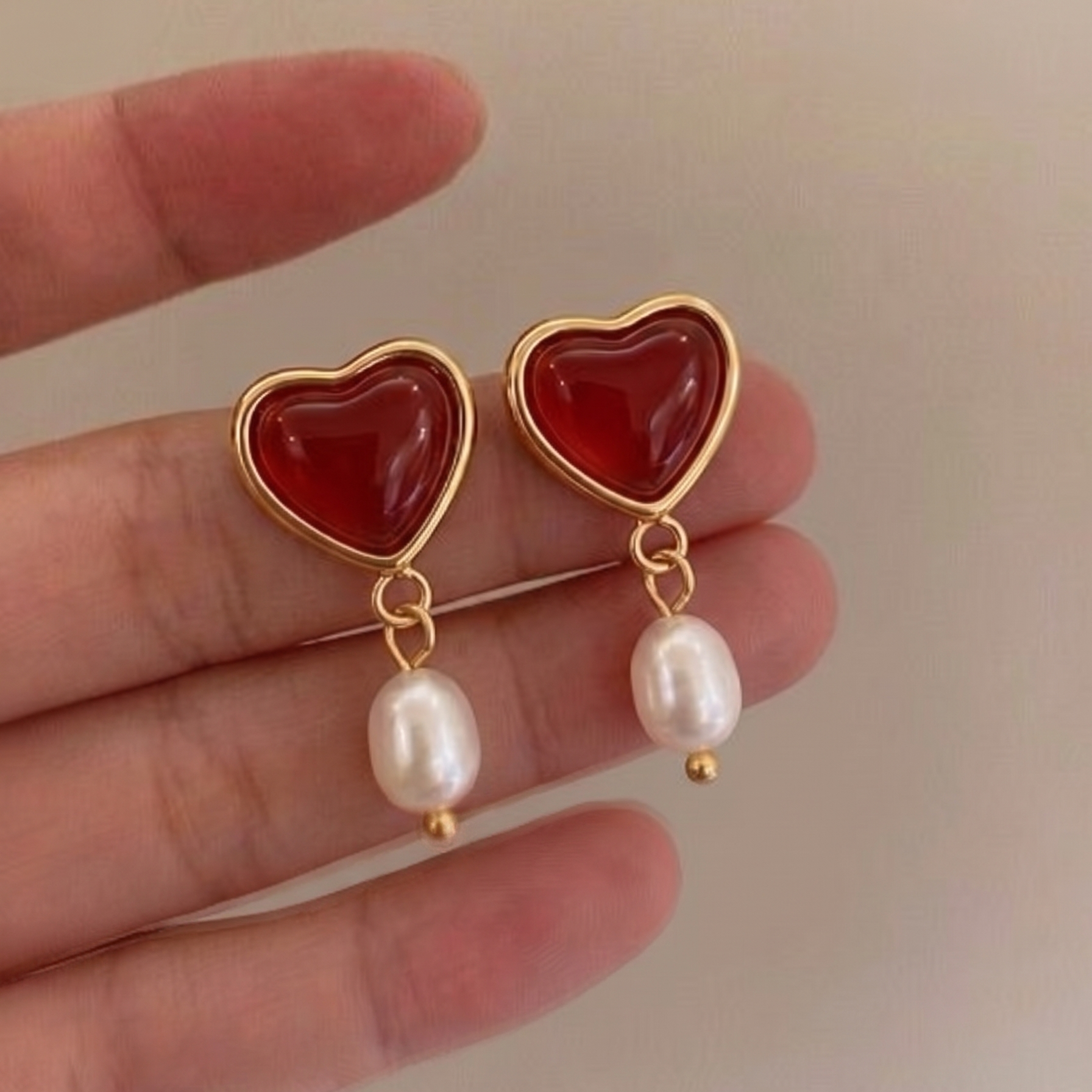 Rouge Drops — red agate and pearl drop earrings held between fingers | THE ARCIVE