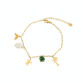 A gold chain anklet featuring tropical and ocean-themed charms, including a mermaid tail, seashell, turtle, palm trees, and a green stone bead, displayed on a clean white background.